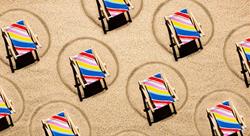 Colorful beach chairs on sand spaced apart for social distancing